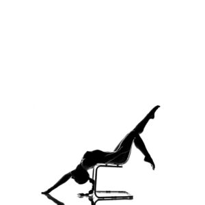 A silhouette of a woman doing yoga on a chair.