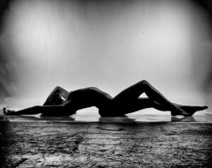 A monochromatic bodyscape of a woman in silhouette, peacefully reclined on the floor.